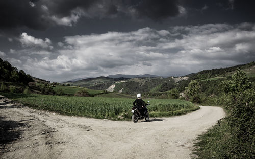 Rear view of man bicycling on road against sky