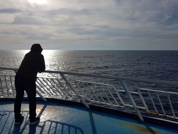 Rear view of man looking at sea against sky