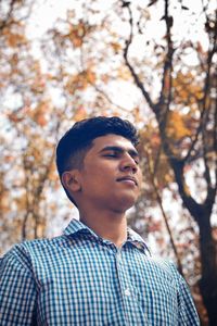 Low angle view of young man against trees