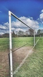 Grassy field against cloudy sky