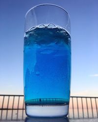 Close-up of glass of ice on table against sea