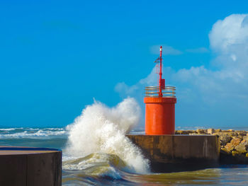 Lighthouse by sea against blue sky