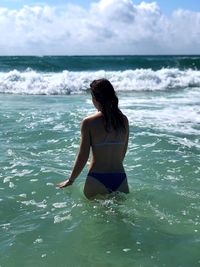 Rear view of woman standing in sea on sunny day