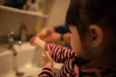 Close-up of cute baby girl washing hands in bathroom