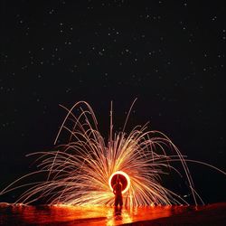 Rear view of man spinning wire wool against star field