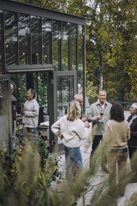 Happy friends talking to each other during dinner party at backyard