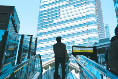 Rear view of man standing by modern buildings in city