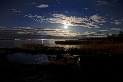 Boat moored on beach against sky during sunset