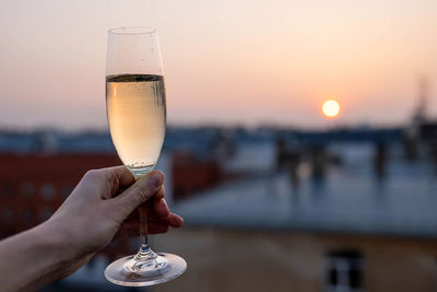 Girl holding a glass of champagne into the sunset.