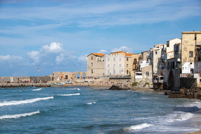 Buildings by sea against sky