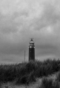 Lighthouse on beach against sky