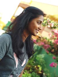 Young woman looking down while standing by flowering plants