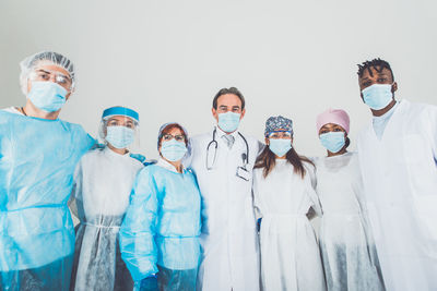 Portrait of doctors wearing mask standing against white background