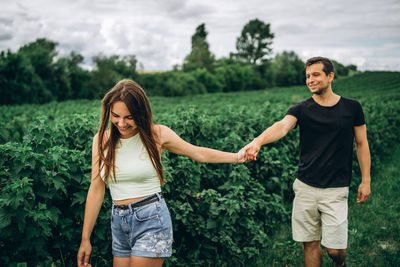 Happy young woman standing against trees