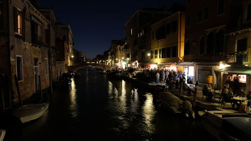 Canal amidst buildings in city at night