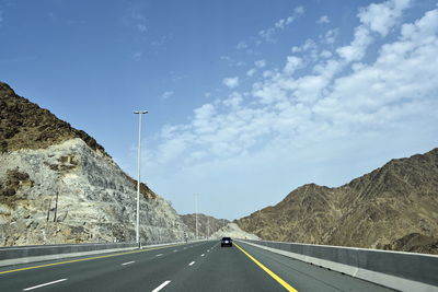 Road leading towards mountain against sky