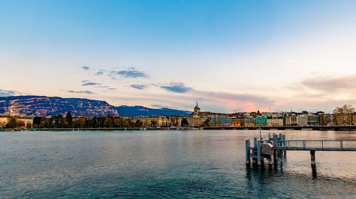 Buildings at waterfront against cloudy sky