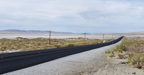 Road leading towards landscape against sky