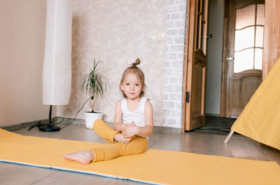 Cute girl sitting on wooden floor at home