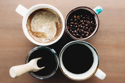 Multiple coffee cups, milk, beans and ground coffee in jar on wooden background. high quality photo