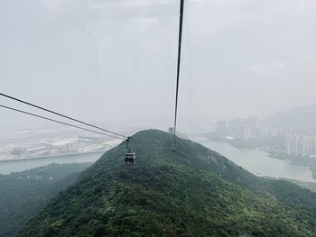 Overhead cable car over mountain against sky