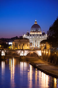 View of illuminated building by river against clear sky