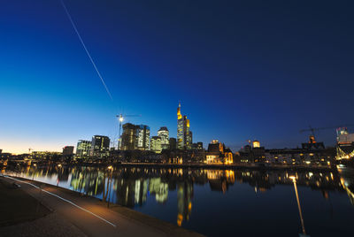 Illuminated buildings against blue sky at night