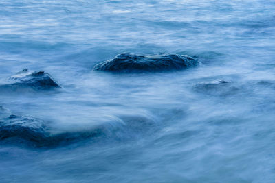 Long exposure smooth ocean wave moving into rock.