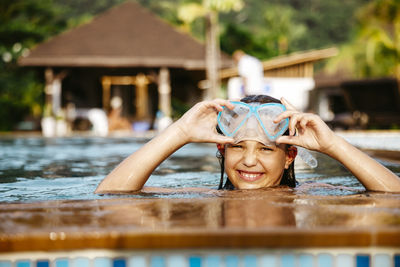 Portrait of smiling girl with swimming googles in pool at resort