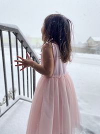 Girl looking away while standing against white snow