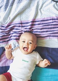 Portrait of cute baby girl lying on bed at home