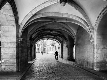 Rear view of man walking in alley amidst buildings in city