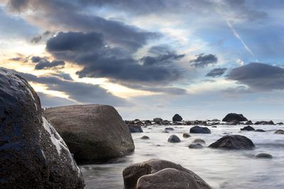 Rocks in sea against sky during sunset