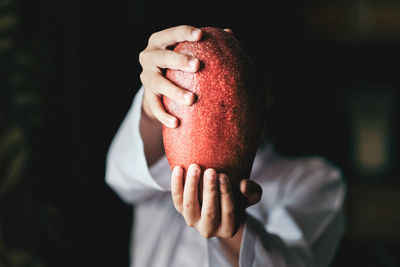 Midsection of man holding ice cream cone against black background