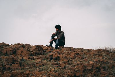 Man standing on rock against sky