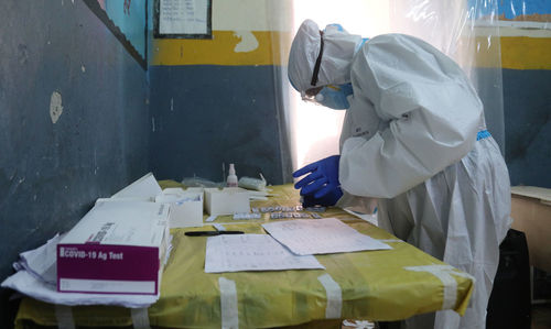 Side view of healthcare worker examining test samples on table