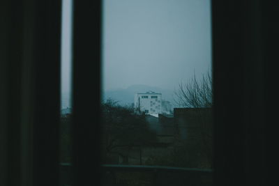 Houses against clear sky seen through window