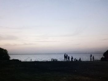 Silhouette people on beach against sky during sunset