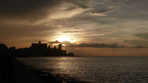 Silhouette of city at waterfront during sunset