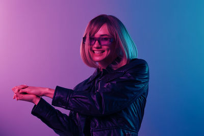 Portrait of young woman standing against blue background