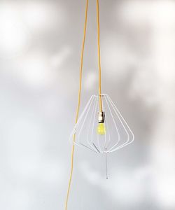 Close-up of yellow wire hanging over white background