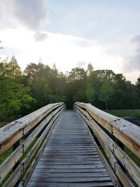 Footbridge amidst trees against sky