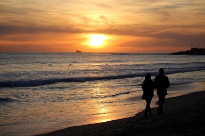 Silhouette of people at beach during sunset