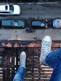 Low section of man standing on metal grate over road