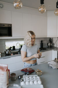 Woman using cell phone in kitchen