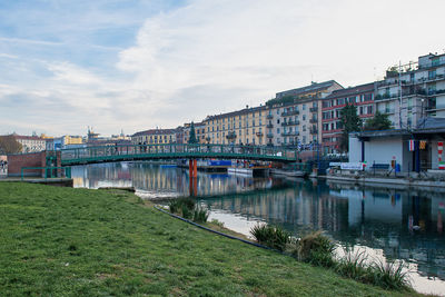 Bridge over river by buildings against sky