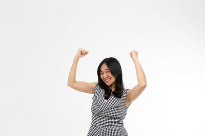 Portrait of young woman standing against white background