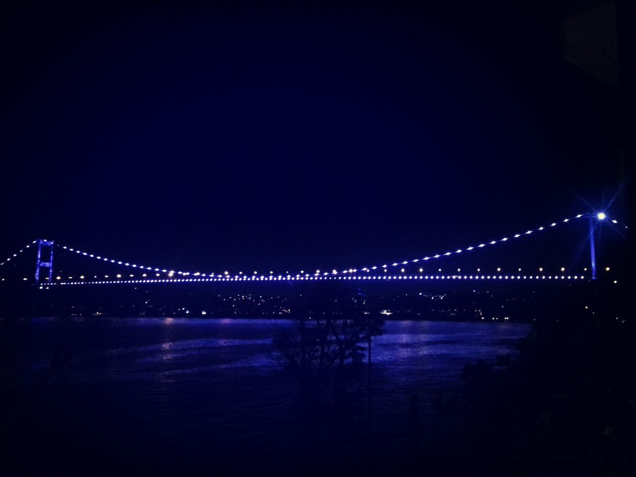 night, illuminated, bridge - man made structure, connection, copy space, water, built structure, architecture, clear sky, reflection, lighting equipment, dark, bridge, river, transportation, waterfront, engineering, street light, light - natural phenomenon, city