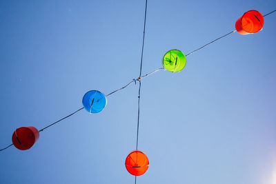 Directly below shot of buckets hanging upside down on cables against clear blue sky