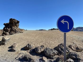 Road sign on rock against clear blue sky